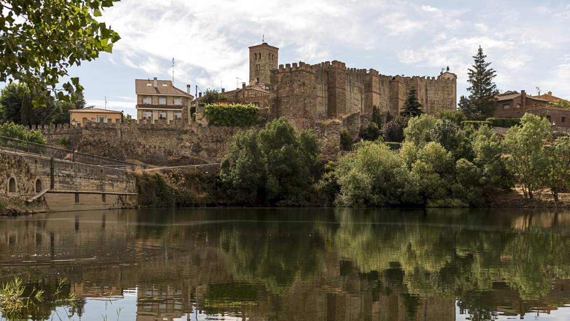 Vista del conjunto medieval de Buitrago del Lozoya en el que puede apreciarse la muralla y el castillo entre la vegetación.