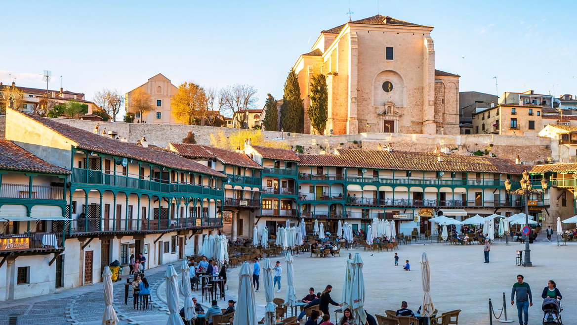 La Plaza Mayor de Chinchón resalta su arquitectura popular castellana en un atardecer rebosante de vida.