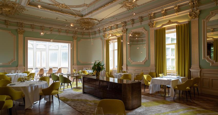 The main dining room of the restaurant mixes a historicist style with modern touches in a colour palette of yellows and greens
