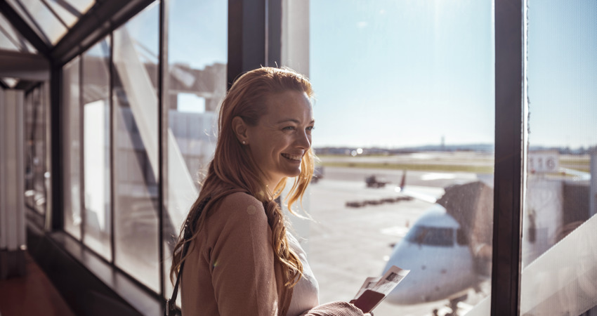 Una mujer a punto de embarcar en un avión de la flota de Iberia con su pasaporte en la mano.