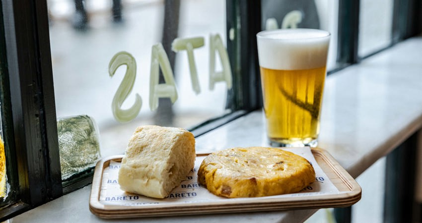 Tapa de tortilla individual con pan y cerveza en Bareto