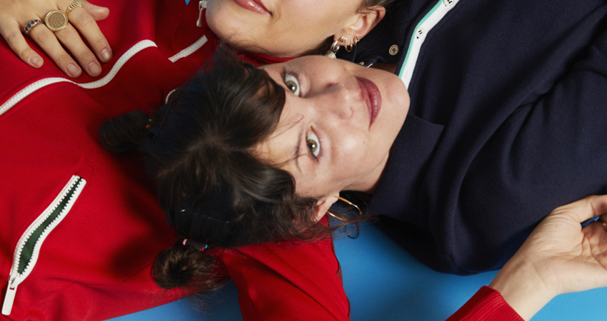 Hinds entrevista. Ana y Carlotta posan juntas, cada una apoyada con la cabeza en el hombro de la otra.
