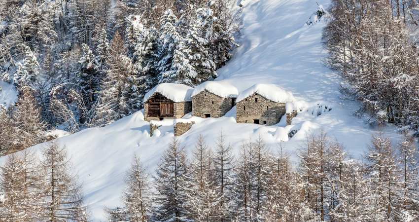 Travel to Milan for 18 750 Avios. In the picture, three wood and stone huts sit on the snowy slope of one of the mountains where you can ski downhill.