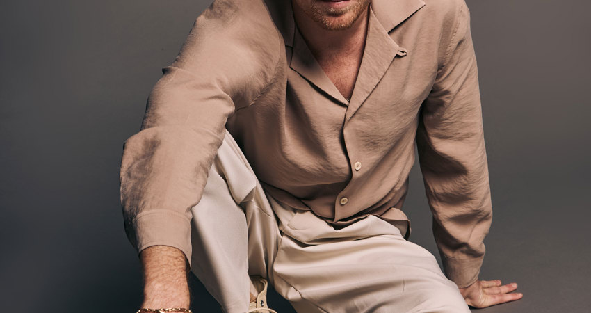Entrevista a Miguel Bernardeau. El actor mira a cámara desde el suelo, sentado en medio del estudio de fotografía.