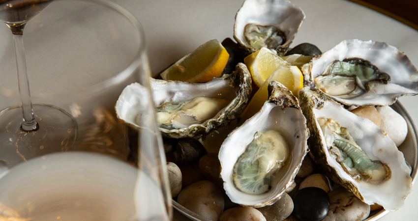 Plato de ostras verdes de Huitres Poget, acompañado de increíbles copas de vino blanco, una especialidad de Barra Alta
