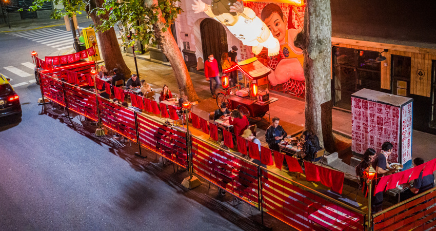 Niño Gordo's outside dinning area, with its characteristic red furniture and its bright lamps in the shape of an adorable child