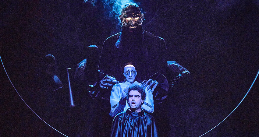 Instantánea de la ópera Orfeo, con uno de los intérpretes cantando en primer plano y un decorado con fantasmas y criaturas mitológicas tras él