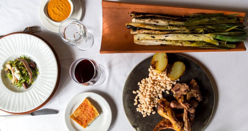 Calçotada típica, con su entrante, sus calçots sobre teja, carne a la brasa, pa amb tomàquet y vino tinto local