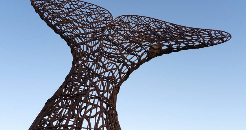 La escultura de Carlos Páez Vilaró se eleva sobre el horizonte al atardecer. La estructura de metal, modelada sobre con tubos a forma de red, reproduce la cola caudal de las ballenas francas