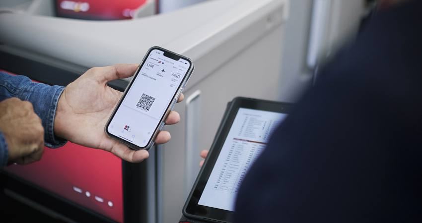 Un pasajero muestra a una azafata de Iberia su tarjeta de embarque dinámica