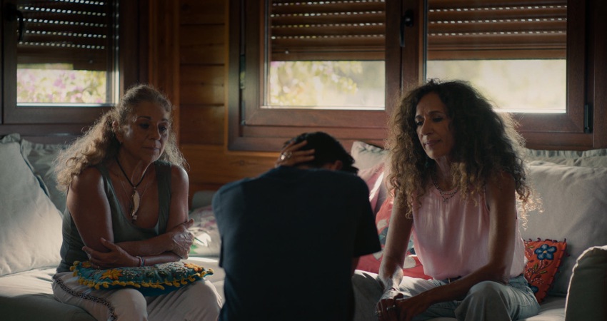 En la imagen, en una habitación en penumbra, Alba se sienta de espaldas a la cámara mientras sus tías Lolita y Rosario, de frente, la miran