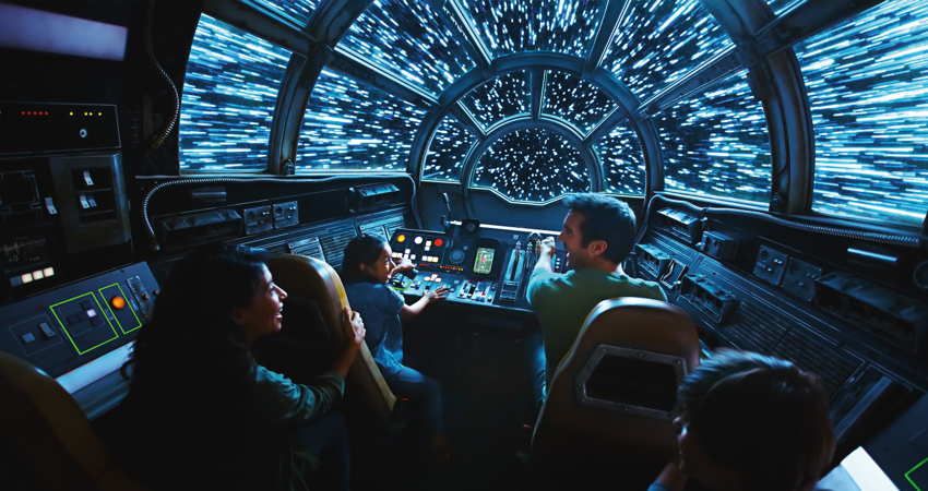 The image shows an adult and two girls sitting at the controls of a spaceship.